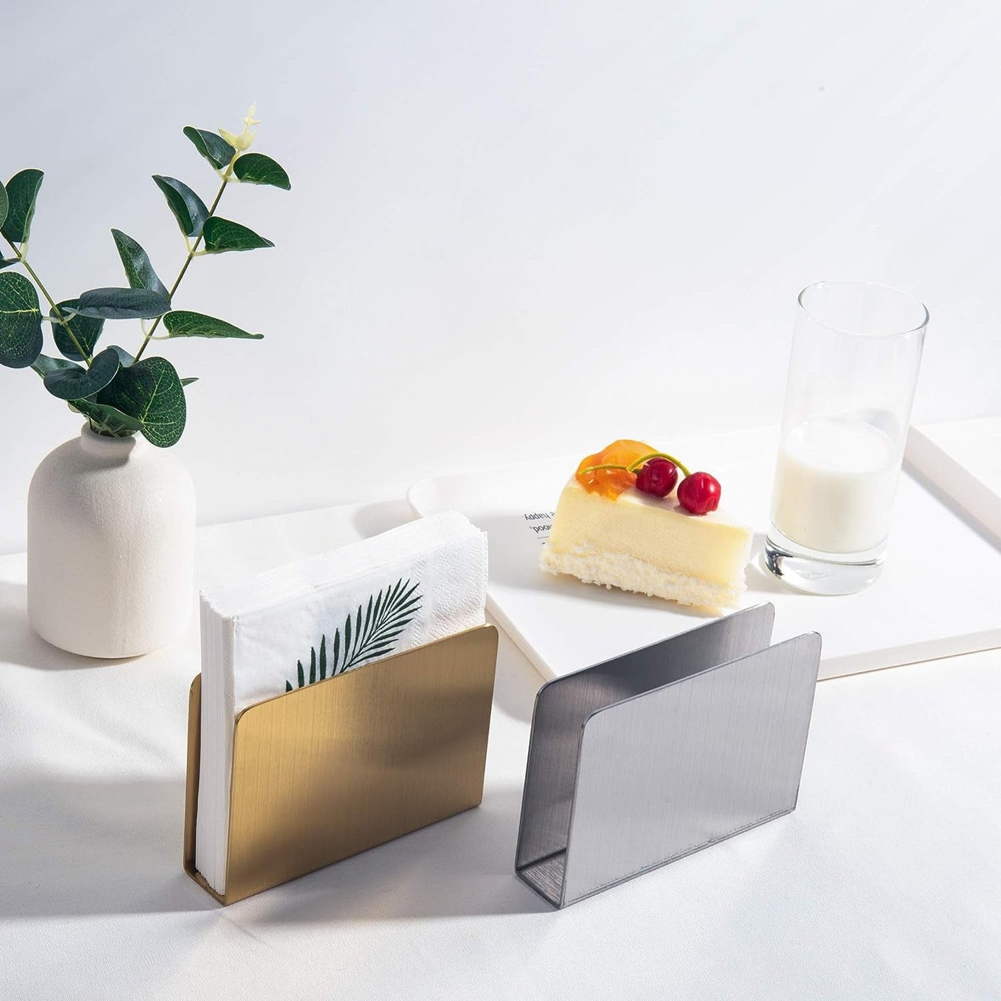 IMEEA gold stainless steel cocktail napkin holder with a silver napkin holder on a table