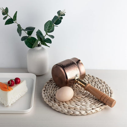 IMEEA Cezve with wooden handle placed on a table mat featuring a simple practical design