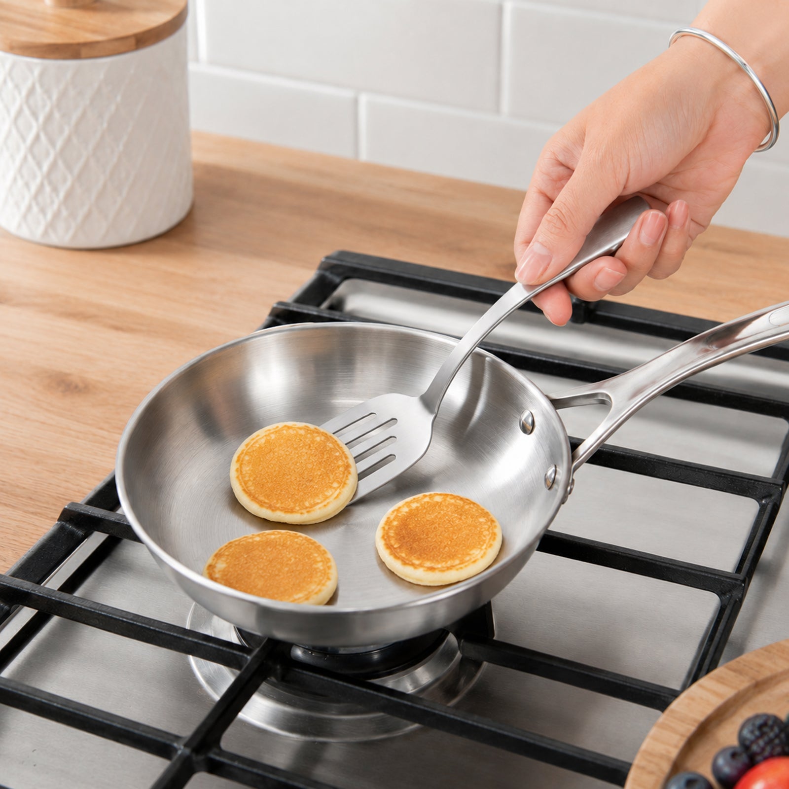 Compact Stainless Steel Mini Turner effortlessly flipping a small pancake in a frying pan