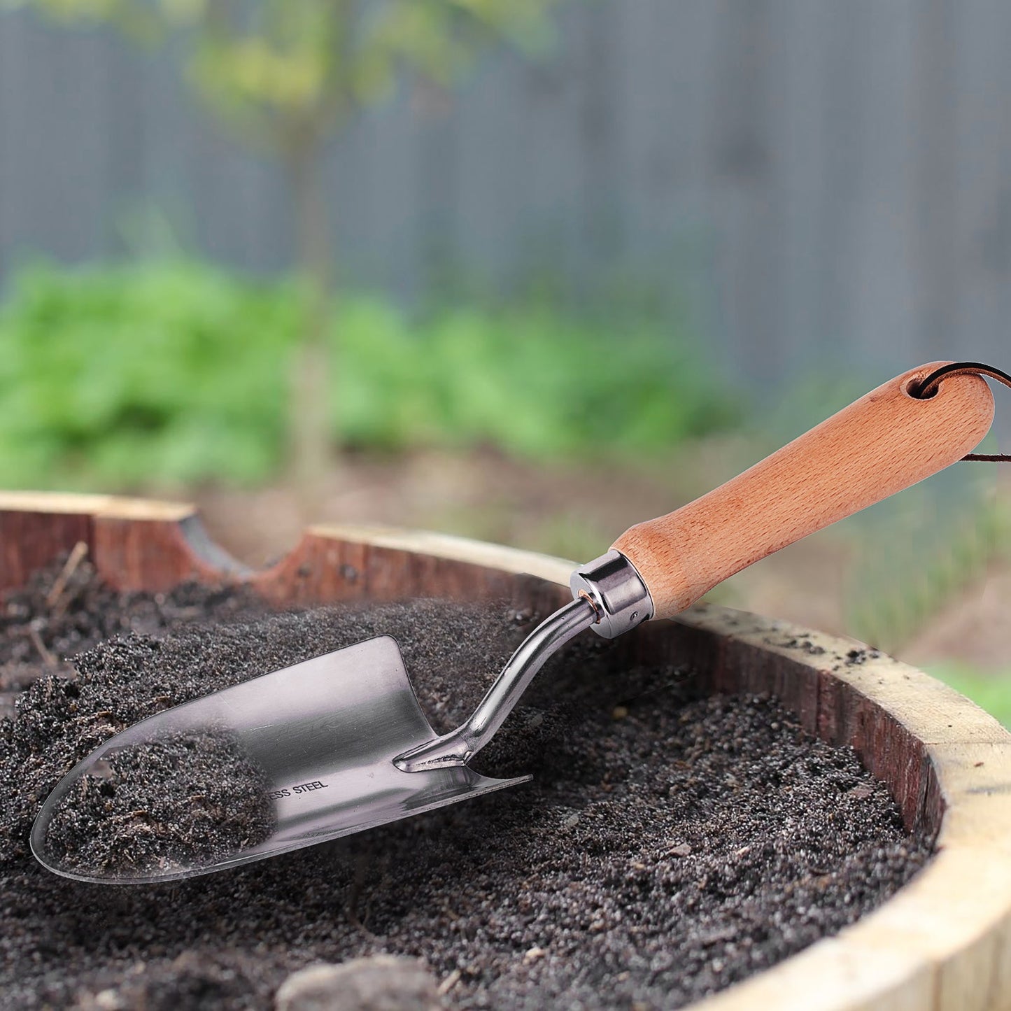 IMEEA Hand Shovel Stainless Planting Trowel scooping soil in a garden for digging and planting tasks