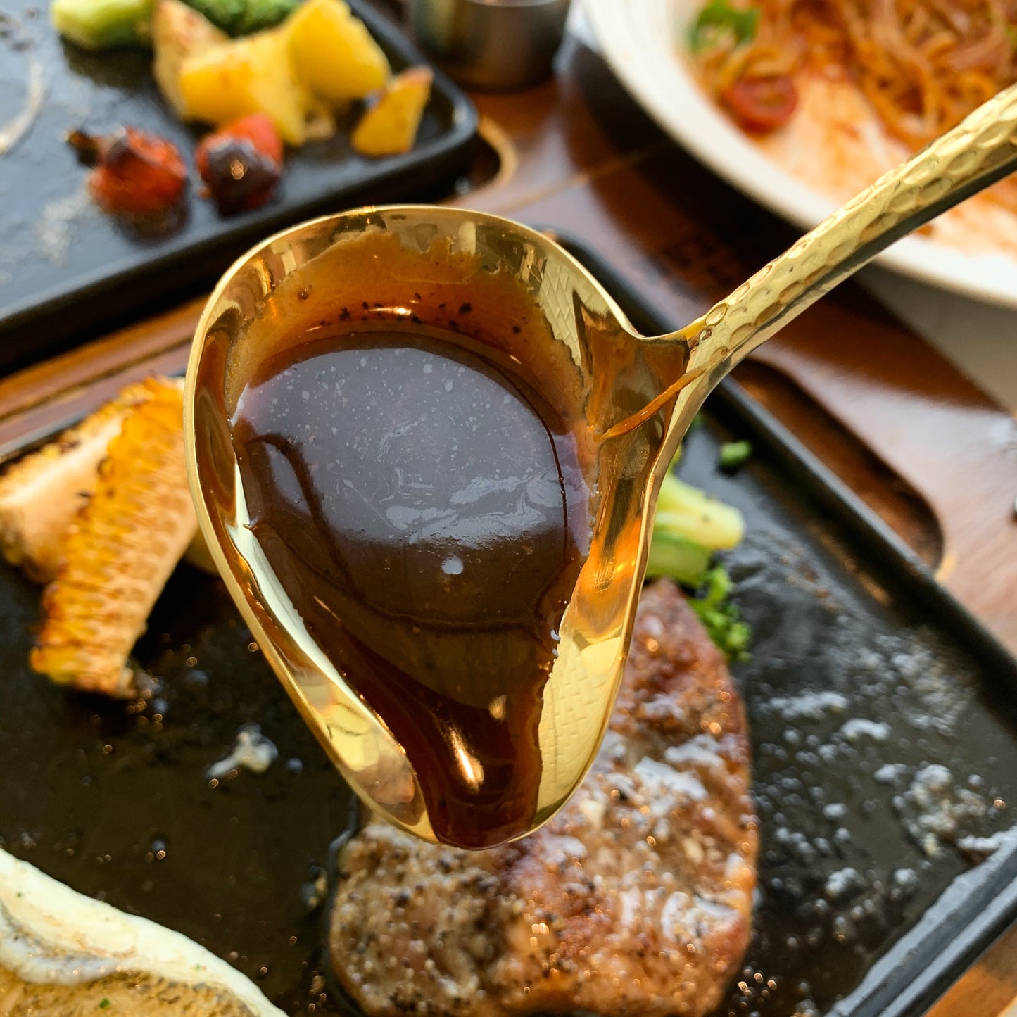 IMEEA gold stainless steel gravy ladle filled with black pepper sauce over steak