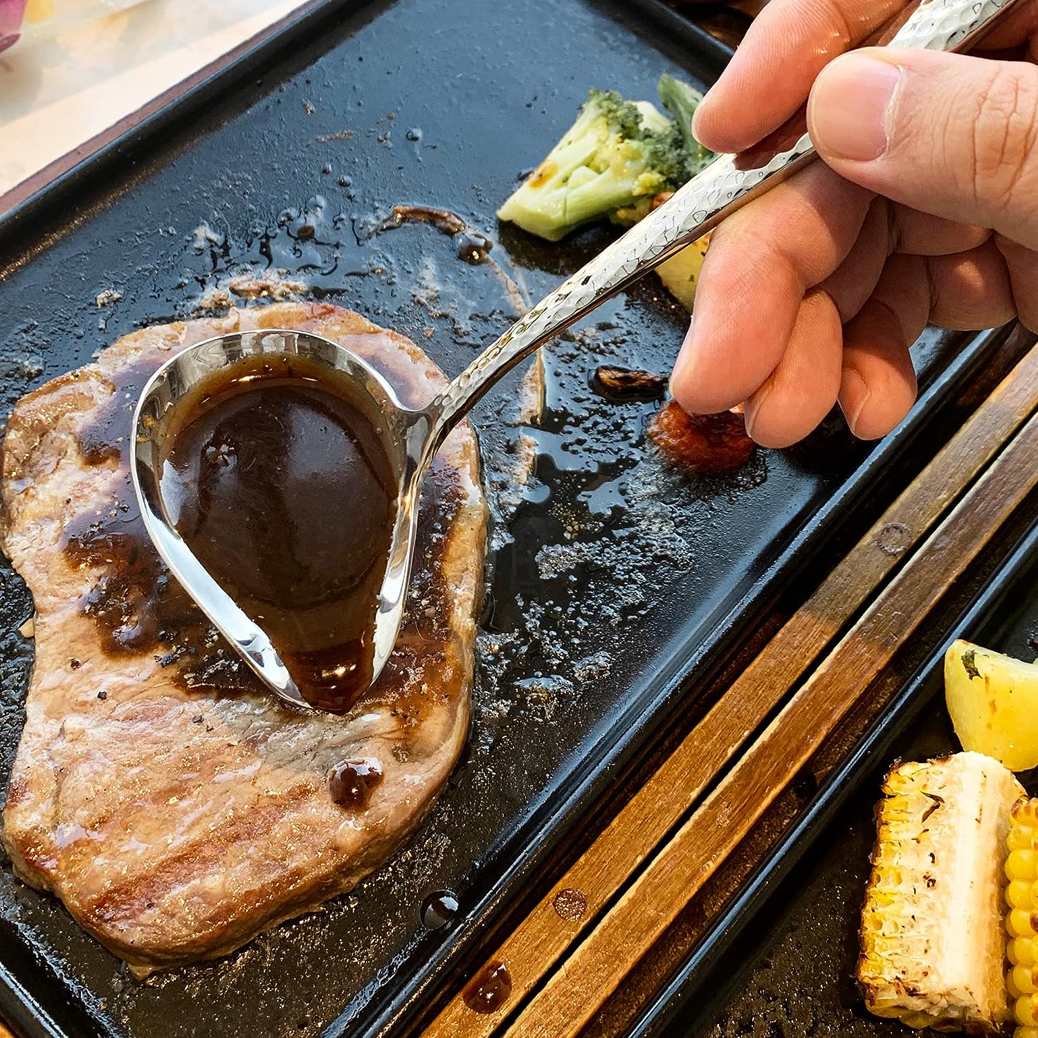IMEEA stainless steel gravy ladle with pour spout being used to drizzle sauce over steak