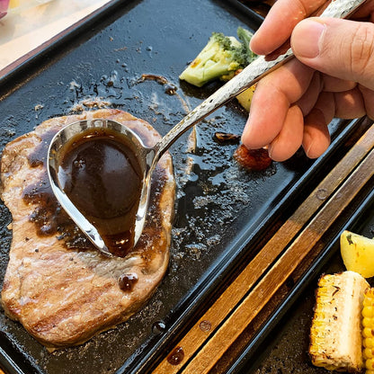 IMEEA stainless steel gravy ladle with pour spout being used to drizzle sauce over steak