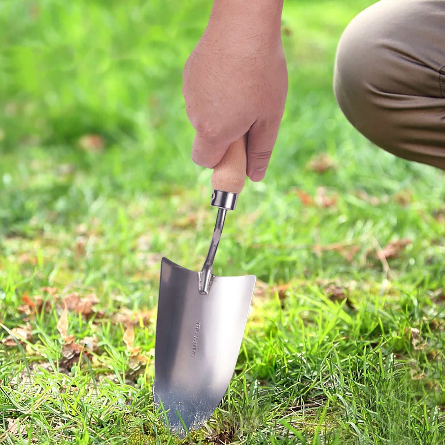 Garden Hand Shovel with stainless steel blade and wooden handle used by hand on grass
