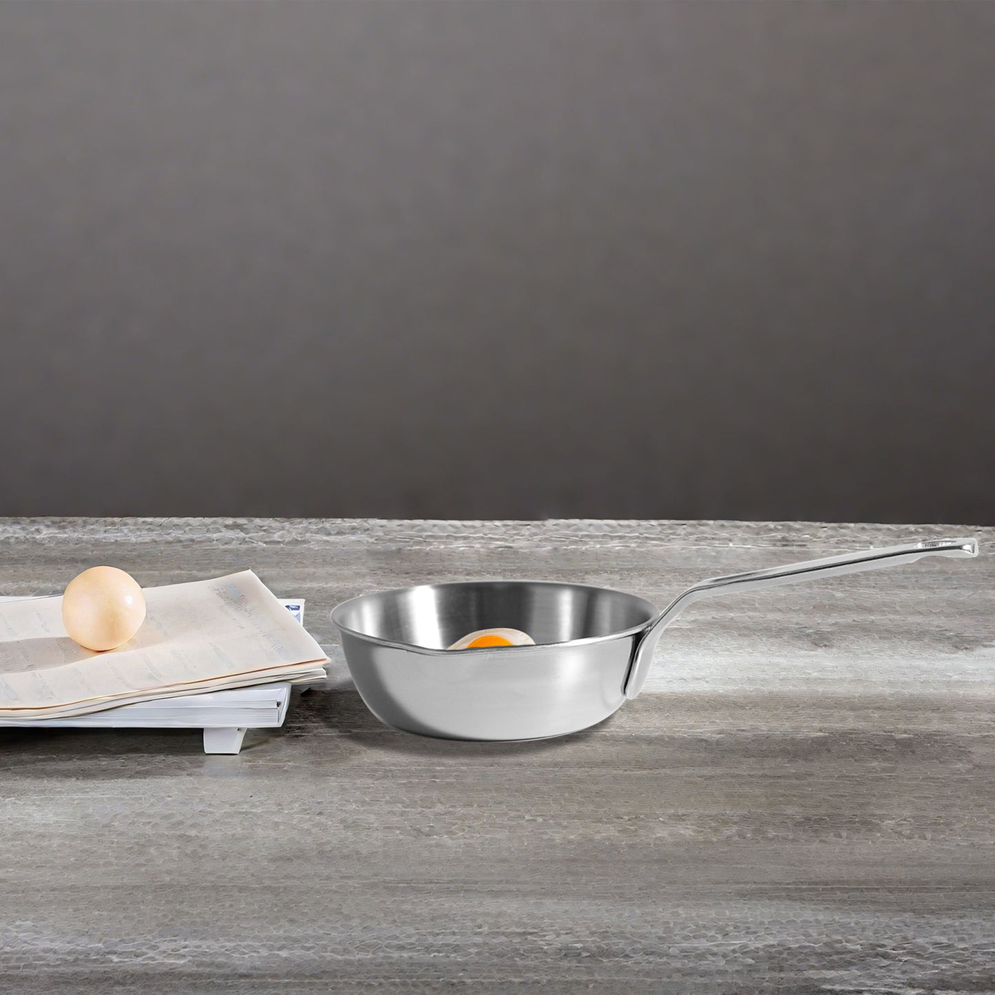 Single Serving Mini Egg Pan on a tabletop with egg and paper for size comparison