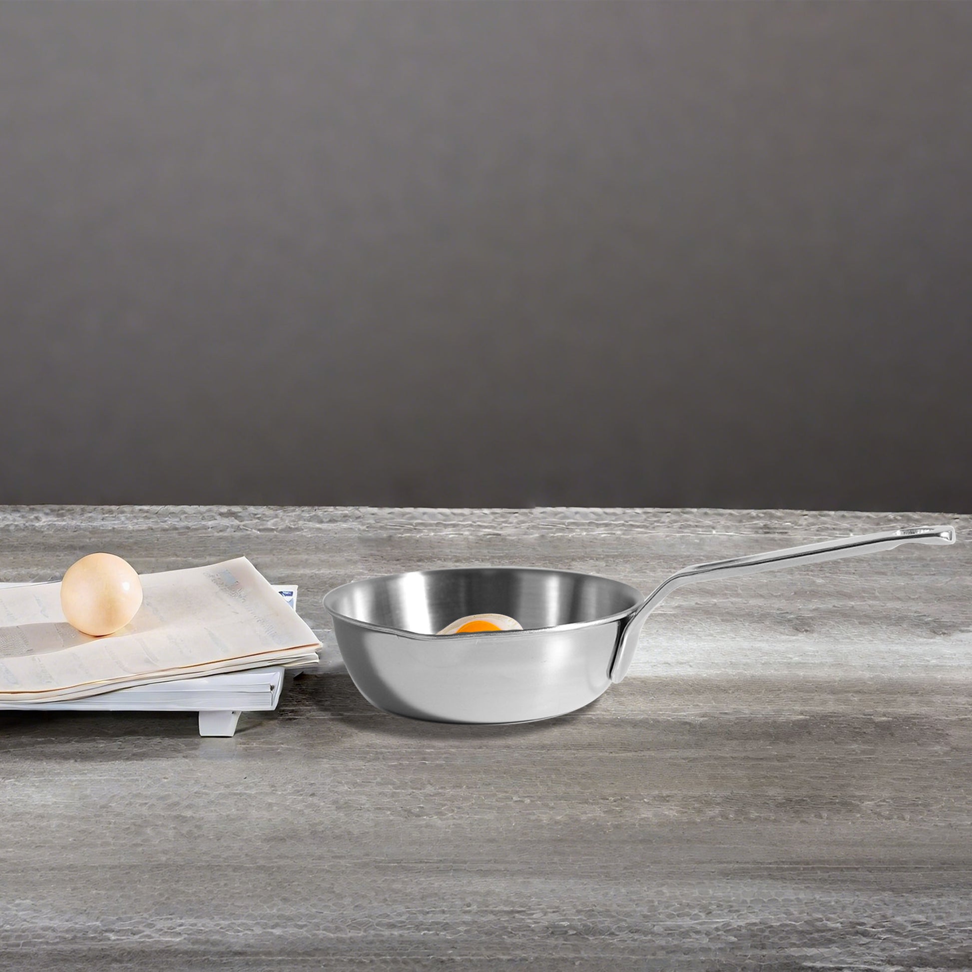 Single Serving Mini Egg Pan on a tabletop with egg and paper for size comparison