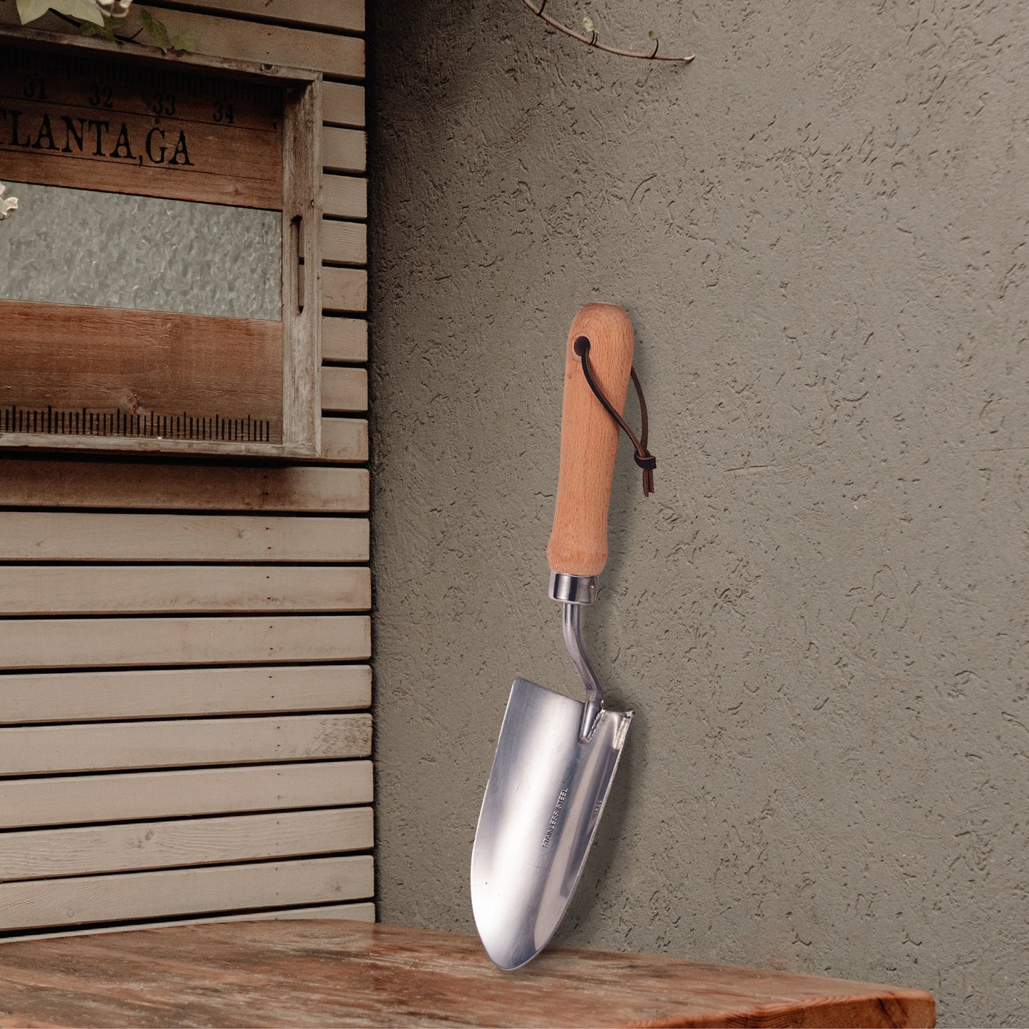 Small Plant Shovel placed in a corner with a sturdy stainless steel blade and wooden handle