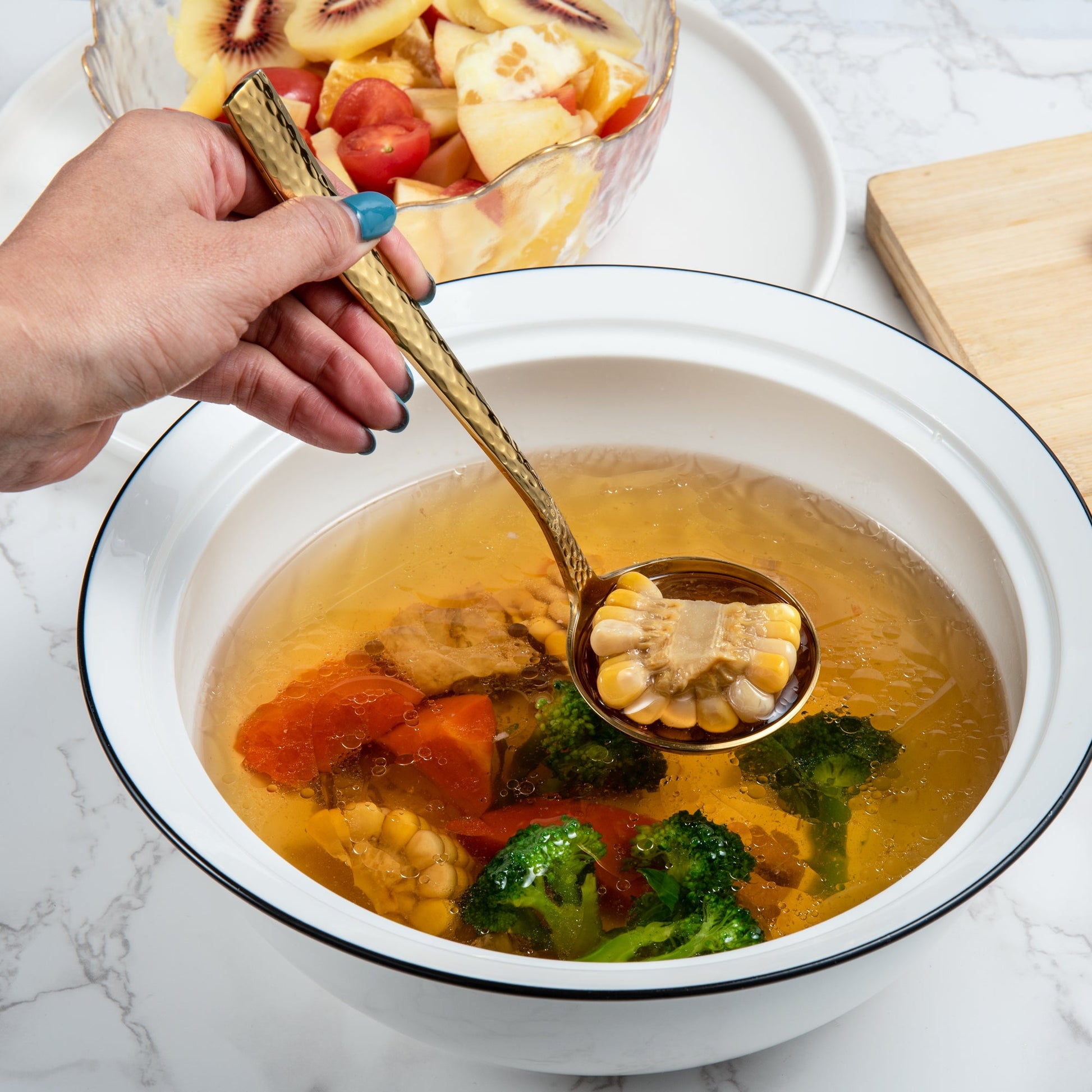 Gold stainless steel sauce ladle scooping corn from soup