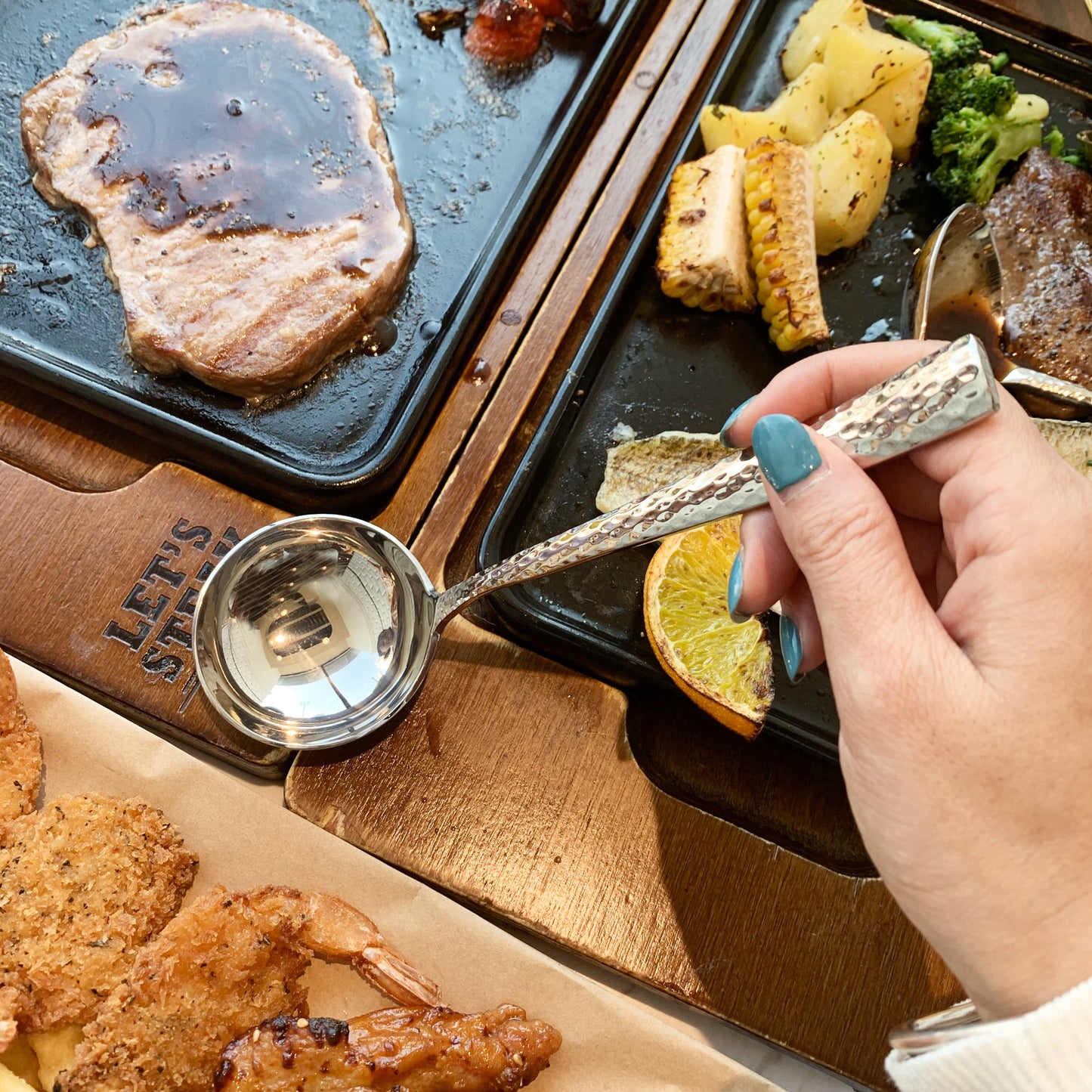 IMEEA simple design stainless steel sauce ladle held by hand on a steak platter