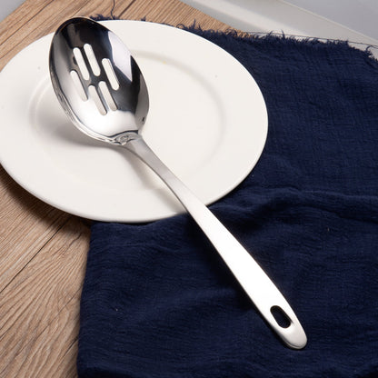 Sllotted serving spoon displayed on a dining plate with a mirror polished finish for elegant food serving