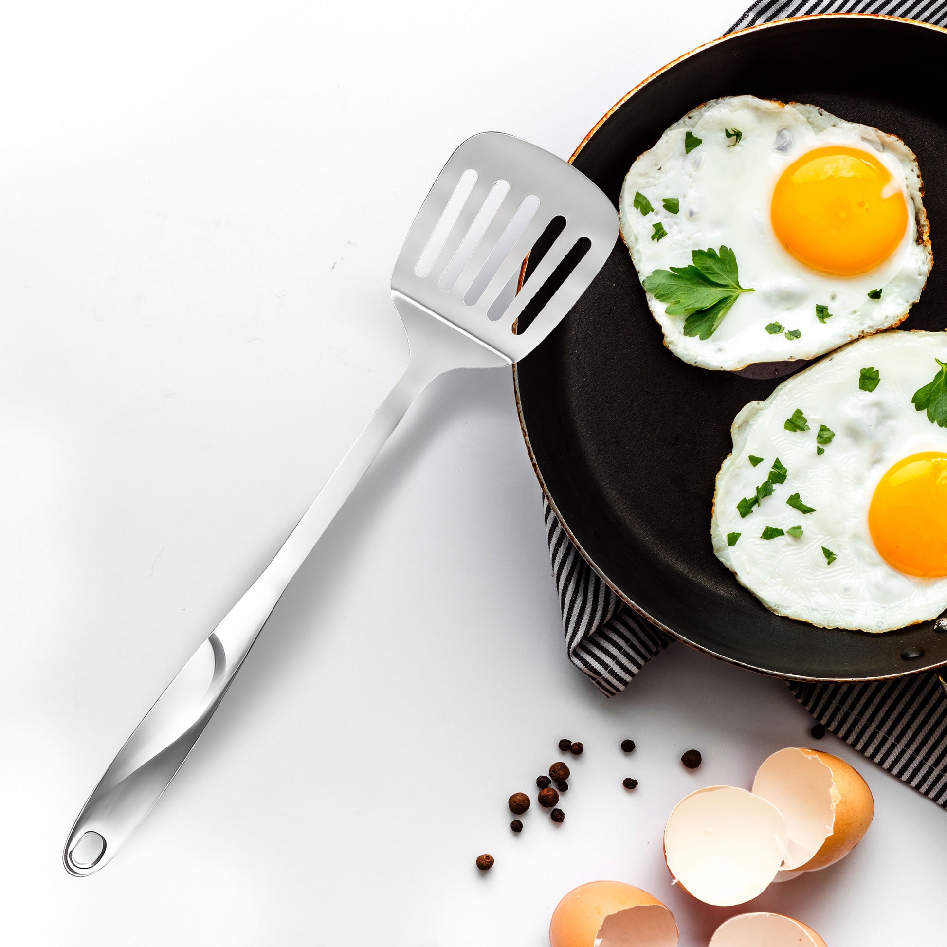 SUS304 Stainless Steel Slotted Spatula beside a pan for breakfast cooking