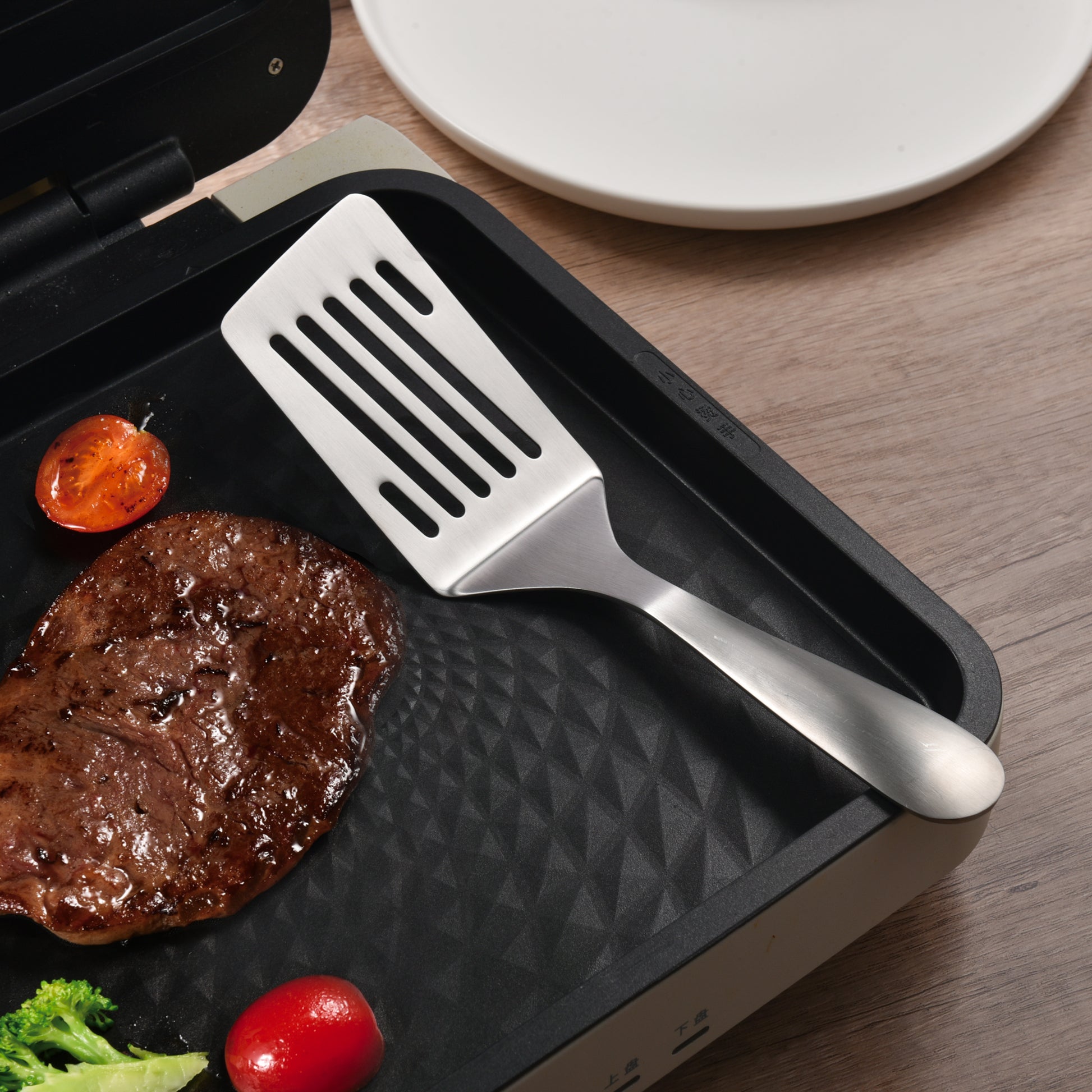 SUS304 Stainless Steel Slotted Spatula placed on a steak frying pan, ready for everyday cooking tasks