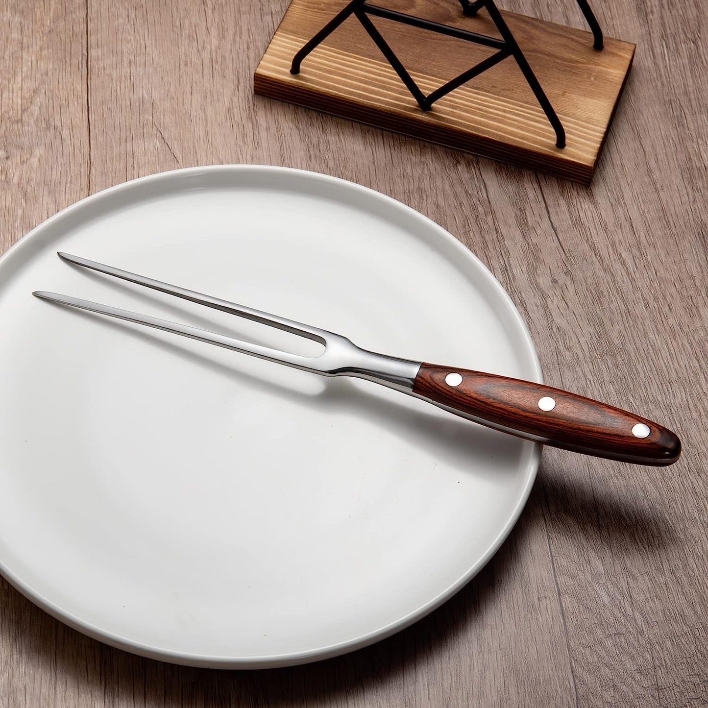 MEEA stainless steel carving fork with wooden handle placed on a plate
