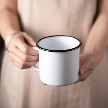 IMEEA Enamel Mug in hand with a comfortable grip, highlighting the simple white finish and everyday usability