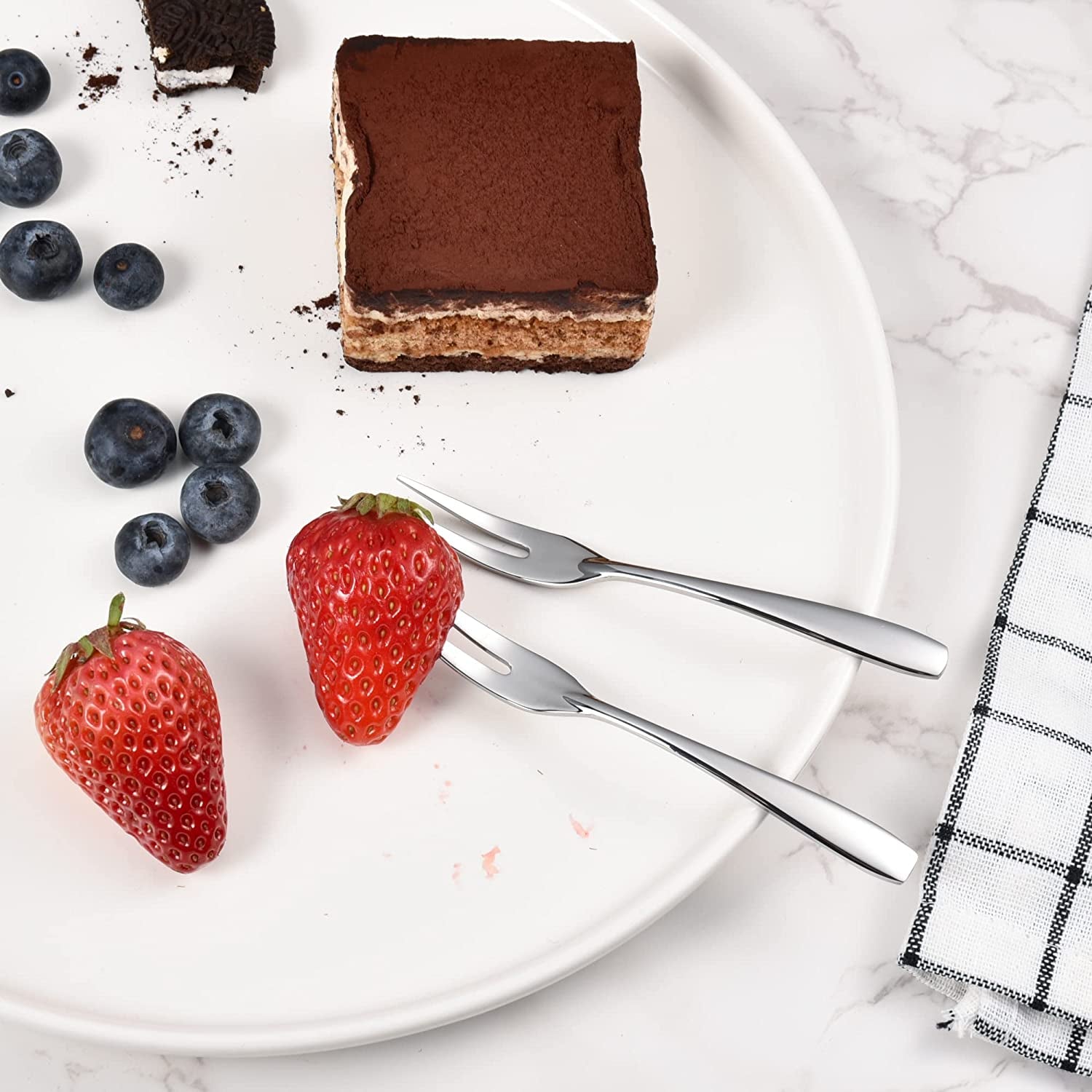 IMEEA Fruit Forks 18/10 Stainless Steel lifting a strawberry from a dessert plate