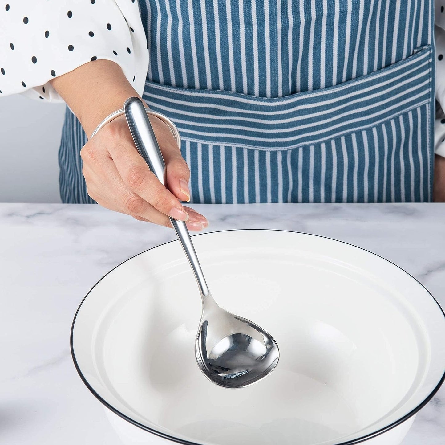 IMEEA SUS304 Stainless Steel Gravy Ladle held by hand inside an empty bowl