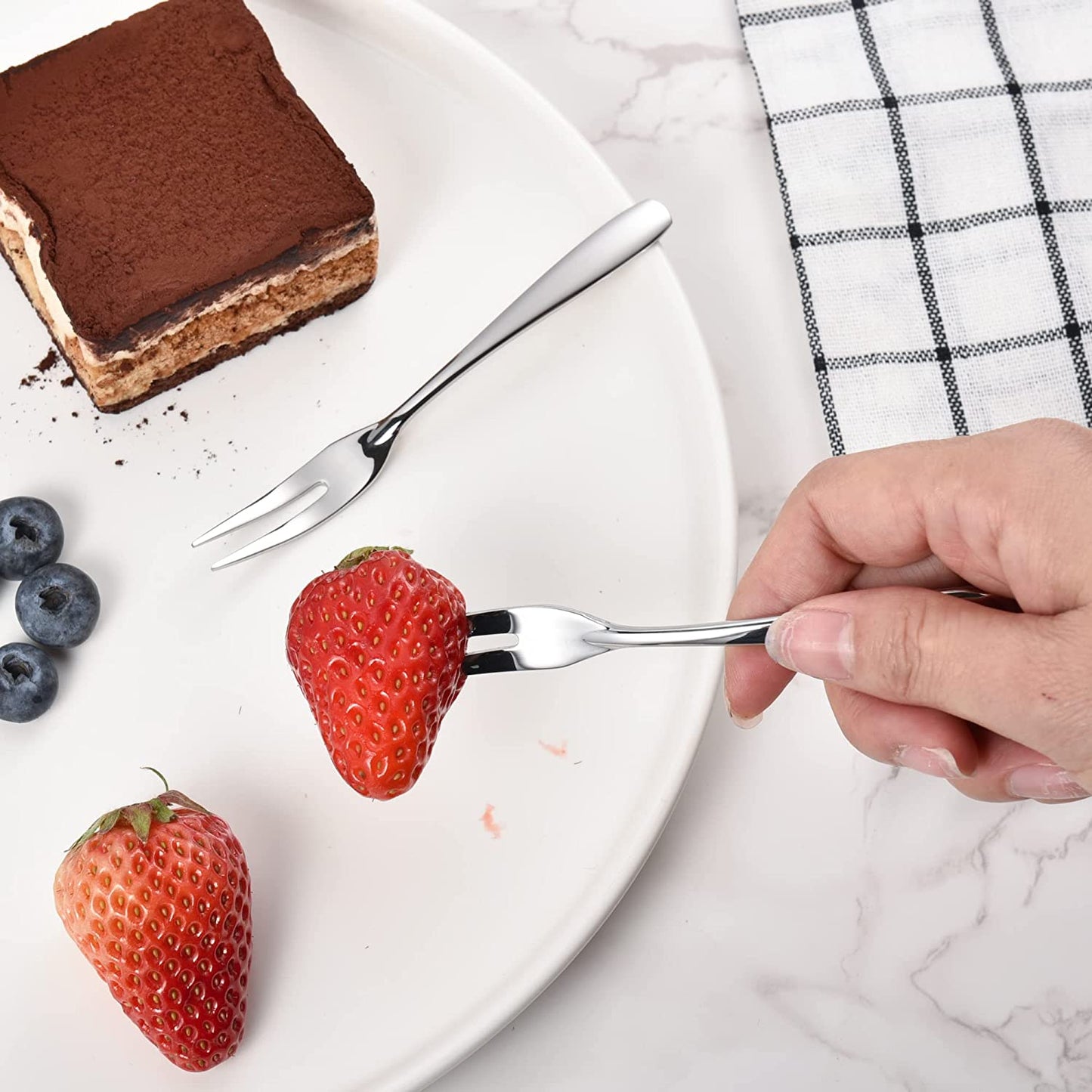 IMEEA Mini Cocktail Forks 18/10 Stainless Steel picking up a strawberry on a plate