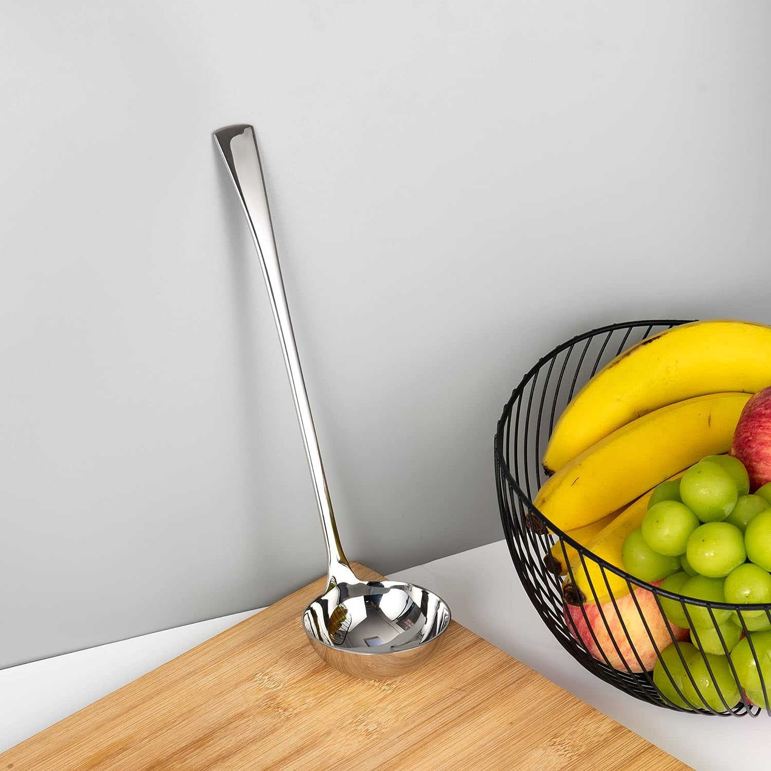 Stainless Steel Serving Ladle placed on a cutting board and leaning against the wall in a kitchen setting